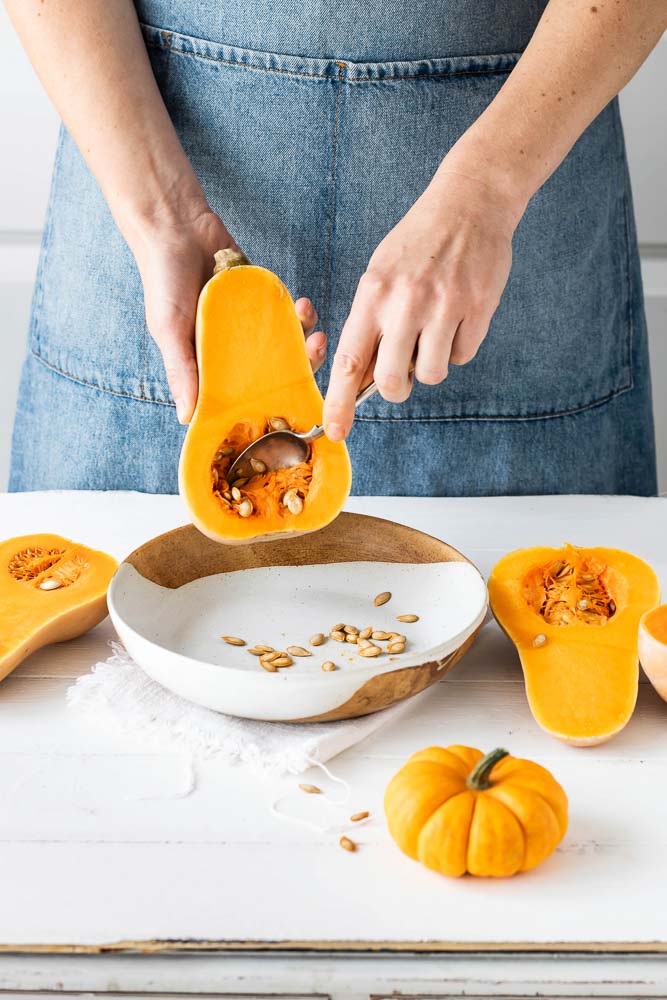 woman removing butternut squash seeds kitchen