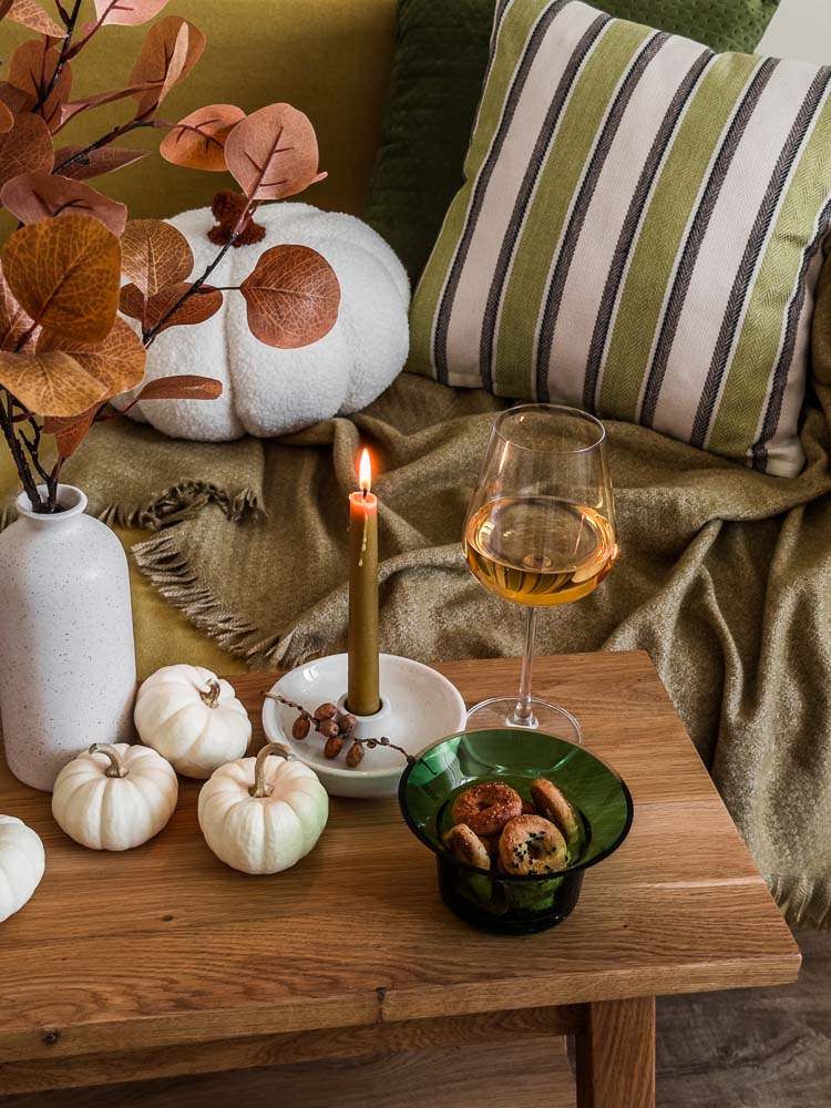 cozy home still life glass wine cookies autumn decor lit candle wooden table near sofa with pillows blankets