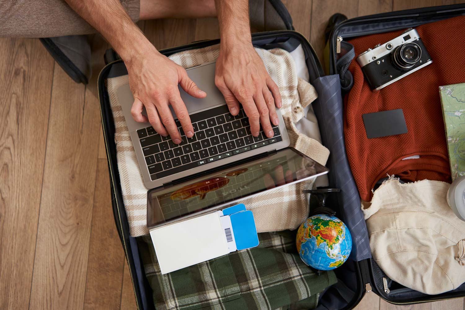 close up tourist hands typing laptop opened suitcase with clothes holiday man packs